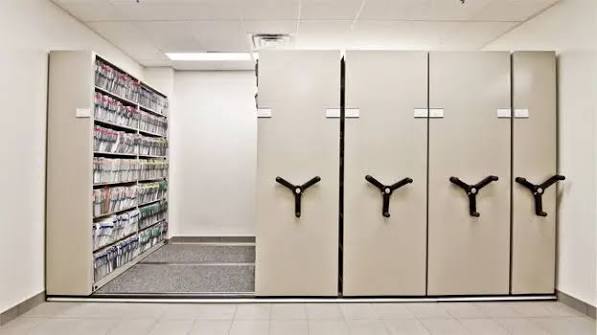 QUADRAMOBILE mechanical-assist mobile shelving in a records room, with one bay open showing archival boxes